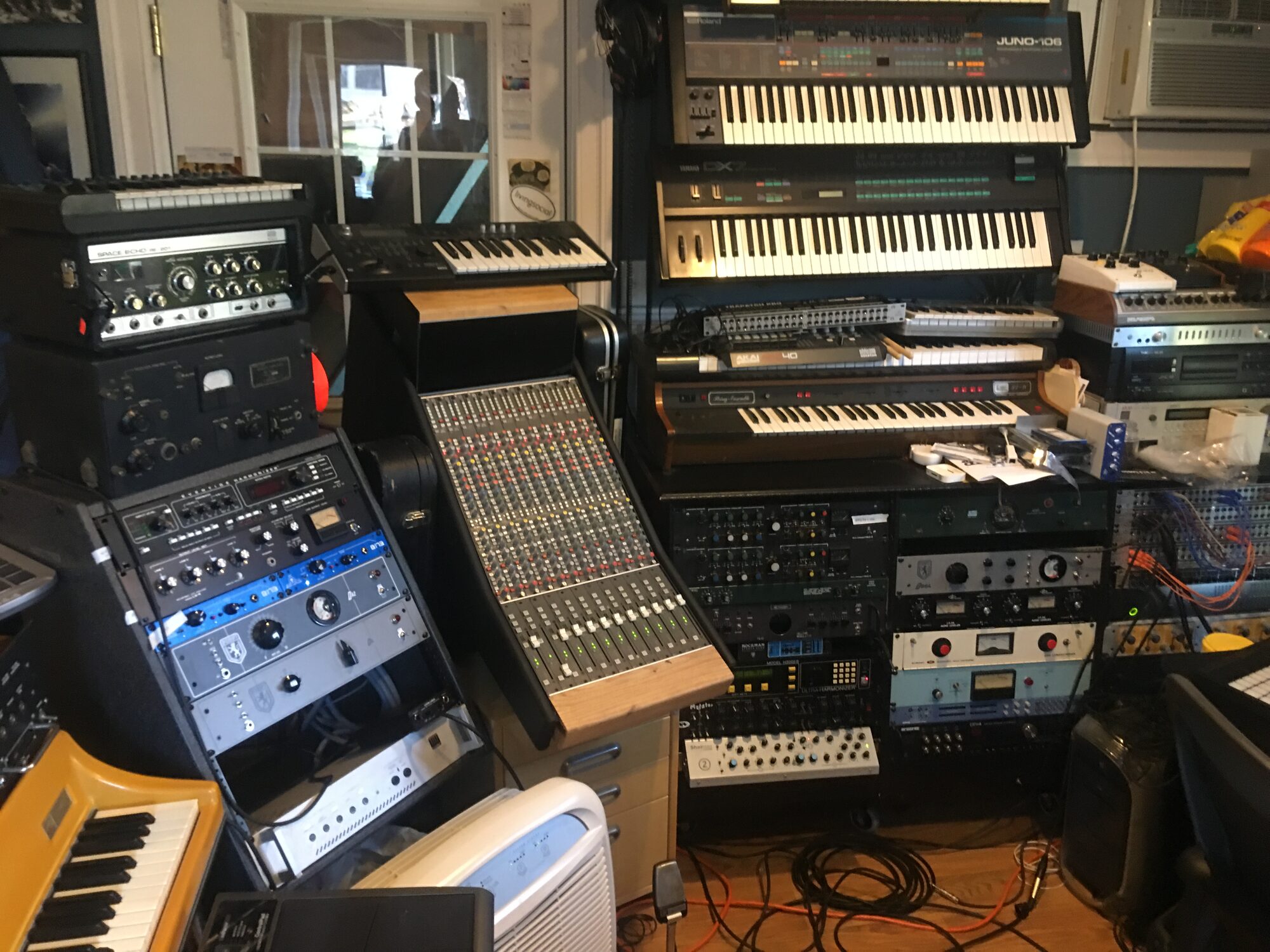Outboard racks, a console, and stacked synths in the studio
